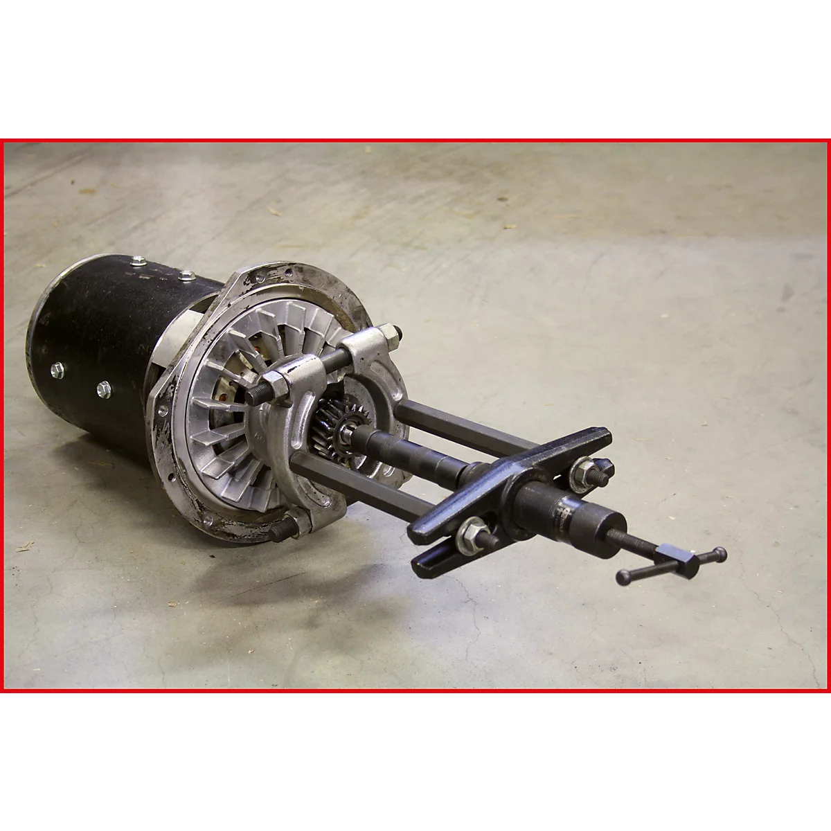 Ein Maschinenteil mit einem schwarzen Gehäuse, einem silberfarbenen Propeller und einem komplexen Mechanismus. Der Hintergrund ist grau.